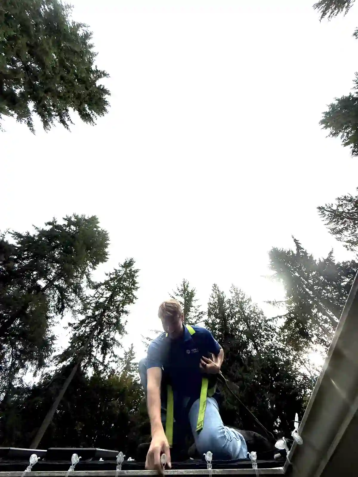 Technician installing holiday lights on a Redmond rooftop